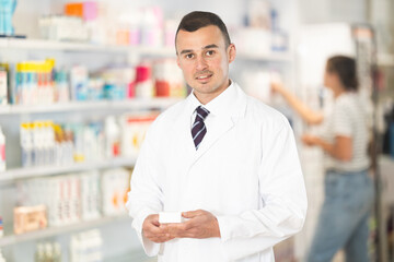 Male pharmacist in medical uniform posing while working in pharmacy