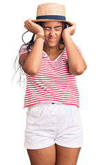 Fototapeta premium Young african american woman with braids wearing summer hat suffering from headache desperate and stressed because pain and migraine. hands on head.