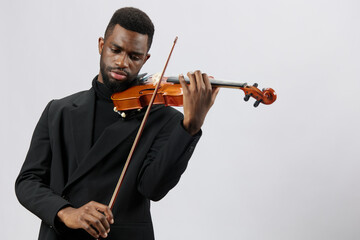 Elegant african american man playing the violin in a black suit on a white background