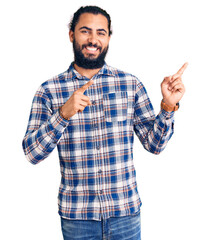 Naklejka premium Young arab man wearing casual clothes smiling and looking at the camera pointing with two hands and fingers to the side.