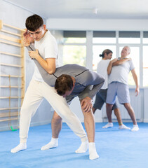 Obraz premium Guy and man during one-on-one training fight are engaged in martial arts section. Fostering strong spirit and sturdy body.