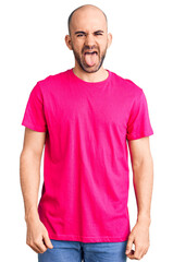 Obraz premium Young handsome man wearing casual t shirt sticking tongue out happy with funny expression. emotion concept.