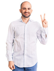 Young handsome man wearing elegant shirt smiling with happy face winking at the camera doing victory sign. number two.