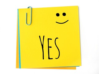 Yes handwritten text and a Happy face on a yellow sticky note 
