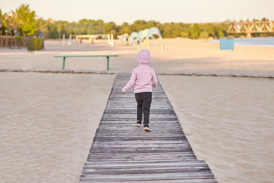 A small child runs along a wooden path on the beach - Powered by Adobe