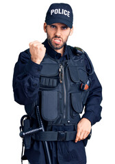 Young handsome man with beard wearing police uniform angry and mad raising fist frustrated and furious while shouting with anger. rage and aggressive concept.