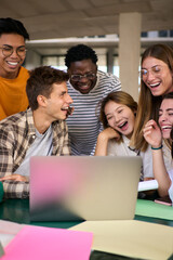 Vertical Group of young diverse students people laughing using laptop in the cafeteria on the university campus. Multiracial classmates working on a creative college project and studying together