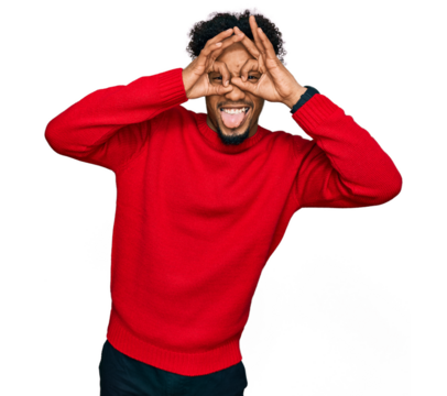 Young african american man with beard wearing casual winter sweater doing ok gesture like binoculars sticking tongue out, eyes looking through fingers. crazy expression.