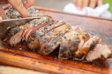 Man using knife to chop cooked beef on a barbecue