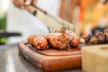 Man using tongs to grab cooked pork sausages
