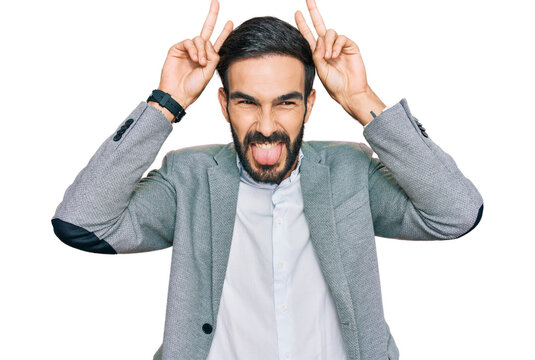 Young hispanic man wearing business clothes posing funny and crazy with fingers on head as bunny ears, smiling cheerful