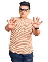 Little boy kid wearing casual clothes and glasses doing stop gesture with hands palms, angry and frustration expression