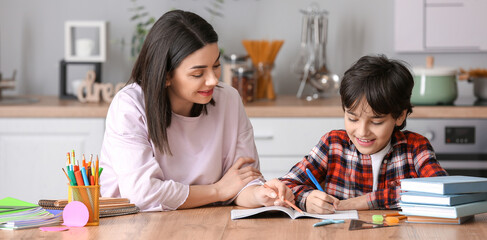 Little boy with his mother doing homework in kitchen