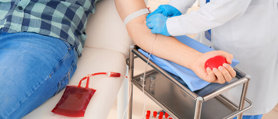Female doctor preparing male donor for blood transfusion in hospital