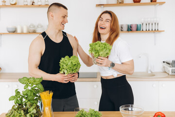 Sporty couple man and woman preparing healthy food in kitchen together