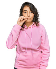 Young hispanic woman wearing casual sweatshirt mouth and lips shut as zip with fingers. secret and silent, taboo talking © Krakenimages.com