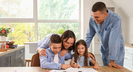 Little children with their parents doing homework in kitchen