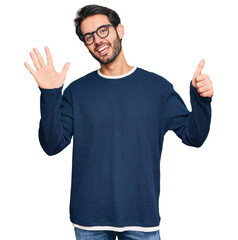 Fototapeta premium Young hispanic man wearing casual clothes and glasses showing and pointing up with fingers number six while smiling confident and happy.
