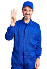 Middle age handsome man wearing mechanic uniform showing and pointing up with fingers number three while smiling confident and happy.