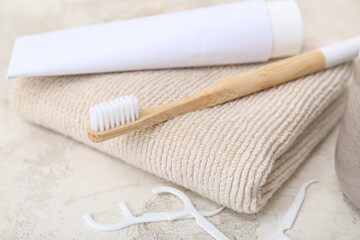 Bamboo toothbrush, paste, towel and floss toothpicks on light background, closeup