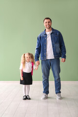 Happy father with his cute little schoolgirl near green wall