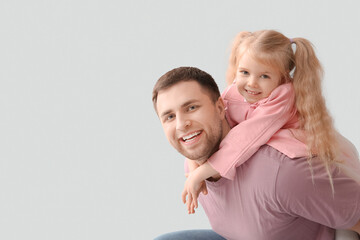Happy father hugging his cute little daughter on grey background