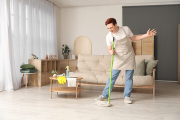 Young man singing while mopping floor in living room