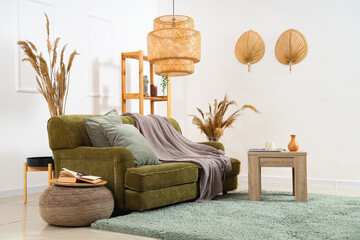Interior of cozy living room with green sofa, table and pampas grass