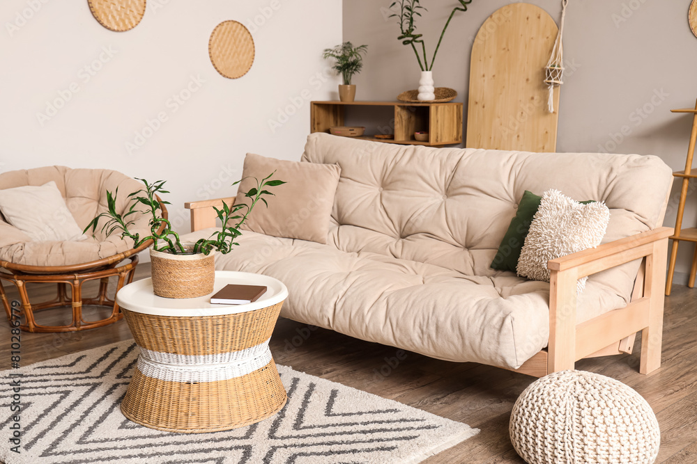 Wall mural Stylish interior of light living room with bamboo stems on coffee table, armchair and white sofa