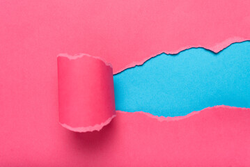 Obraz premium Pink torn paper revealing blue background. Space for text.