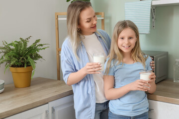 Happy daughter and her mother with cups of milk in kitchen