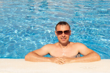 man swims and has fun near a beautiful pool at a resort during vacation. blue background, sea background