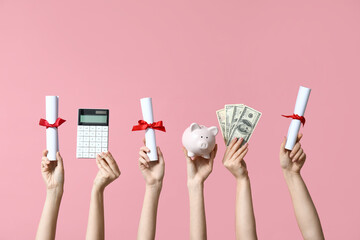 Female hands holding diplomas, money, calculator and piggy bank on pink background
