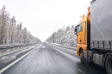 The truck is driving on the road, snow on the trees. The truck is in motion, light blur, fast driving effect.