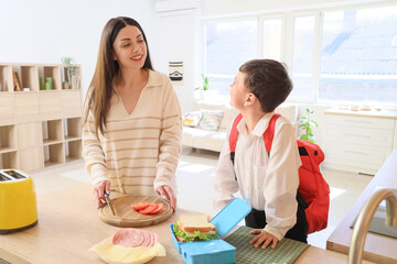 Happy mother with her little son making sandwich for school lunch in kitchen