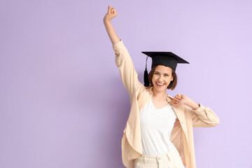 Happy female student in graduation hat on lilac background