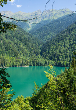 bright turquoise water of lake Ritsa among green hills in Abkhazia on a sunny summer day