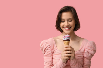 Beautiful young woman with sweet ice-cream in waffle cone on pink background