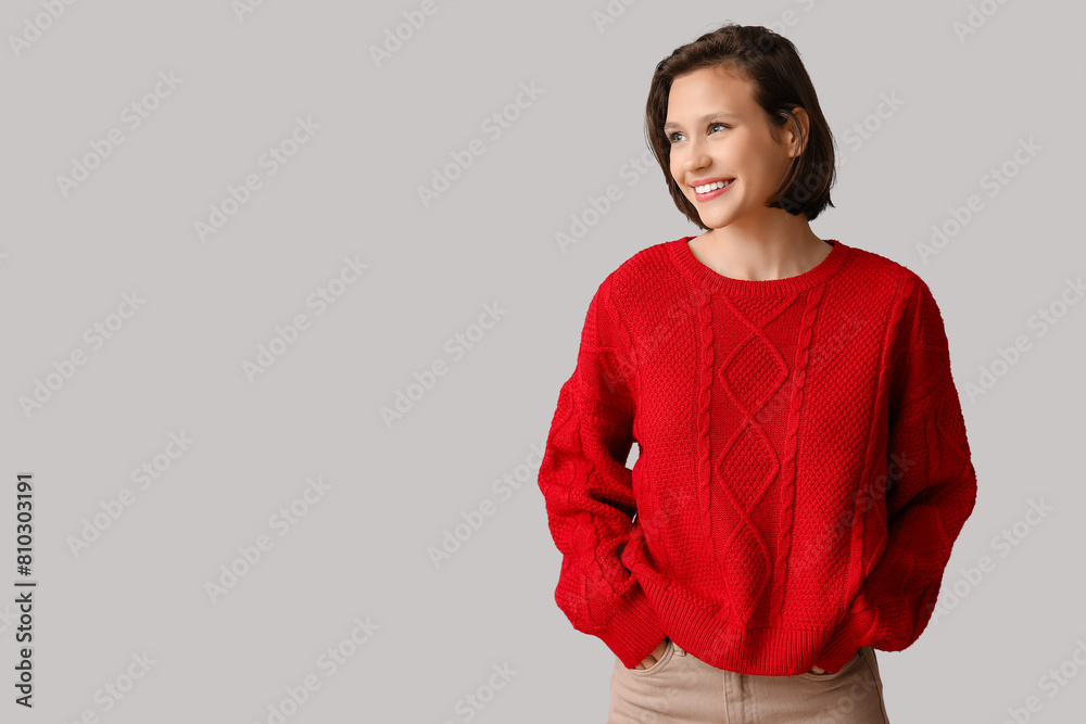 Poster beautiful young woman in stylish red sweater on grey background