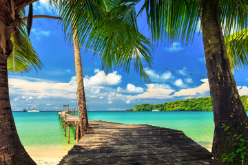 Tranquil and idyllic tropical beach paradise with wooden jetty. Palm trees