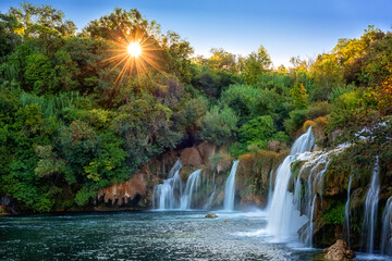 Sunset over tranquil waterfalls and lush forest