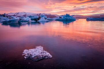 Stunning twilight hues reflect over a serene glacial lagoon with floating icebergs