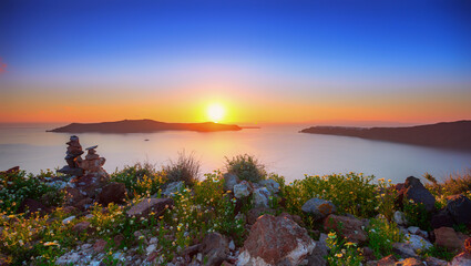 Captivating sunset view with wildflowers and the aegean sea in santorini, greece
