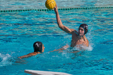 High School water polo player shooting the ball.
