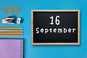 September 16 written in chalk on black board. Calendar date 16th of September on chalkboard on blue blurred school stationery background. Back to school. School event schedule date. Month of autumn.