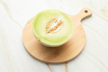 Cut Organic Honeydew Melon On Wooden Cutting Board on Granite Table, Cucumis Melo Inodorus Group. Ripe Nutritious Summer Juicy Fruit. Horizontal Plane. Harvesting, Top View