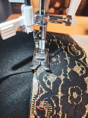 Vintage black and gold sewing machine presser foot meticulously crafting intricate patterns on...