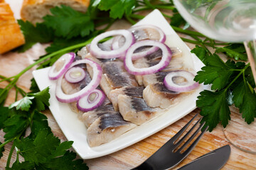 Marinated herring fillet with sliced onion and parsley, healthy food