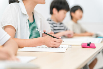 塾・学校の授業中にノートに記入する女の子・小学生・中学生の男女
