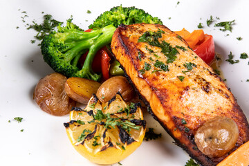 A grilled salmon filet with vegetable garnish on a white table